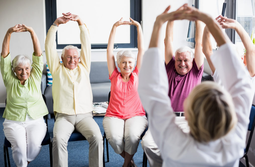 Senior women leading other seniors on yoga session
