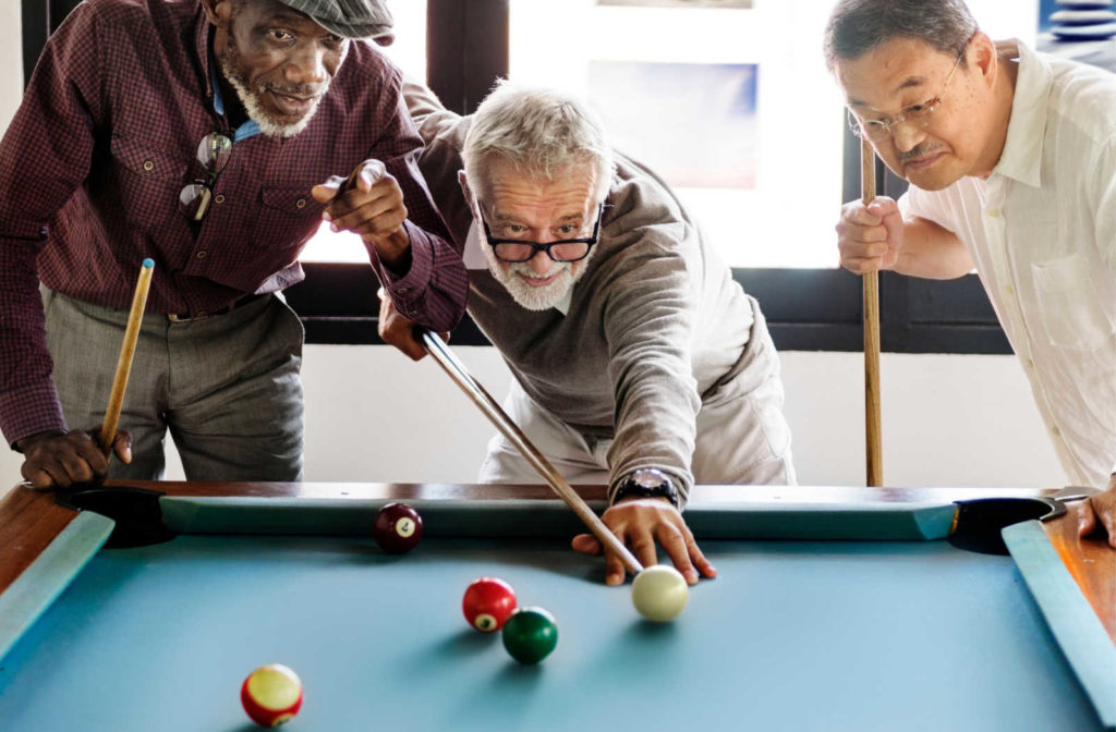 A group of elderly men engaged in a game of billiards.