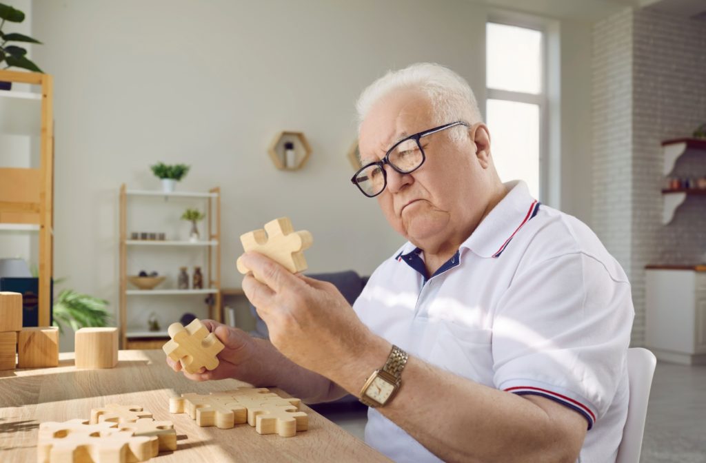 a man is working on a puzzle and has a confused look on his face due to dementia symptoms.